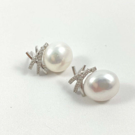 A pair of stud earrings featuring large, lustrous white freshwater pearls set in silver-toned metal with small clear pavé stones, shown on a plain light gray background.