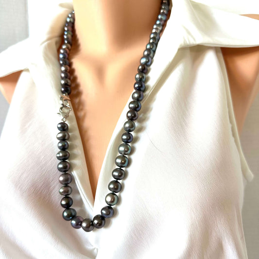 A dark gray pearl necklace with a silver-toned clasp, displayed on a mannequin torso wearing a white blouse.