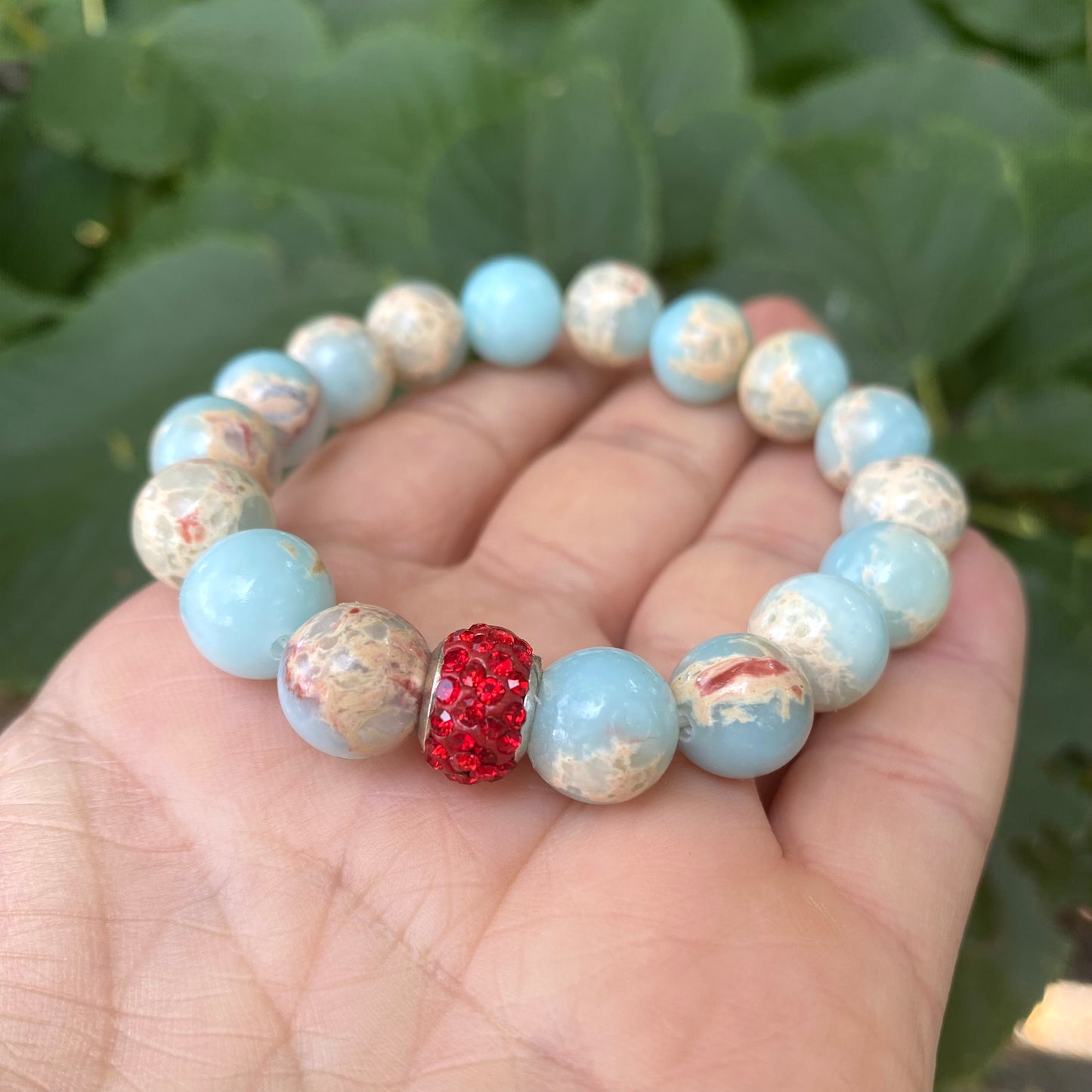 Pale blue deep red stretchy bracelet displayed showing contrast of pale blue and red beads