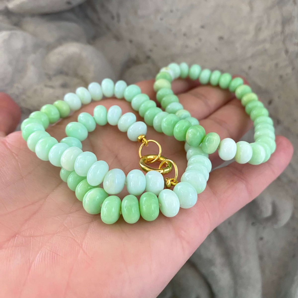 Green opal beaded necklace close-up against stone statue