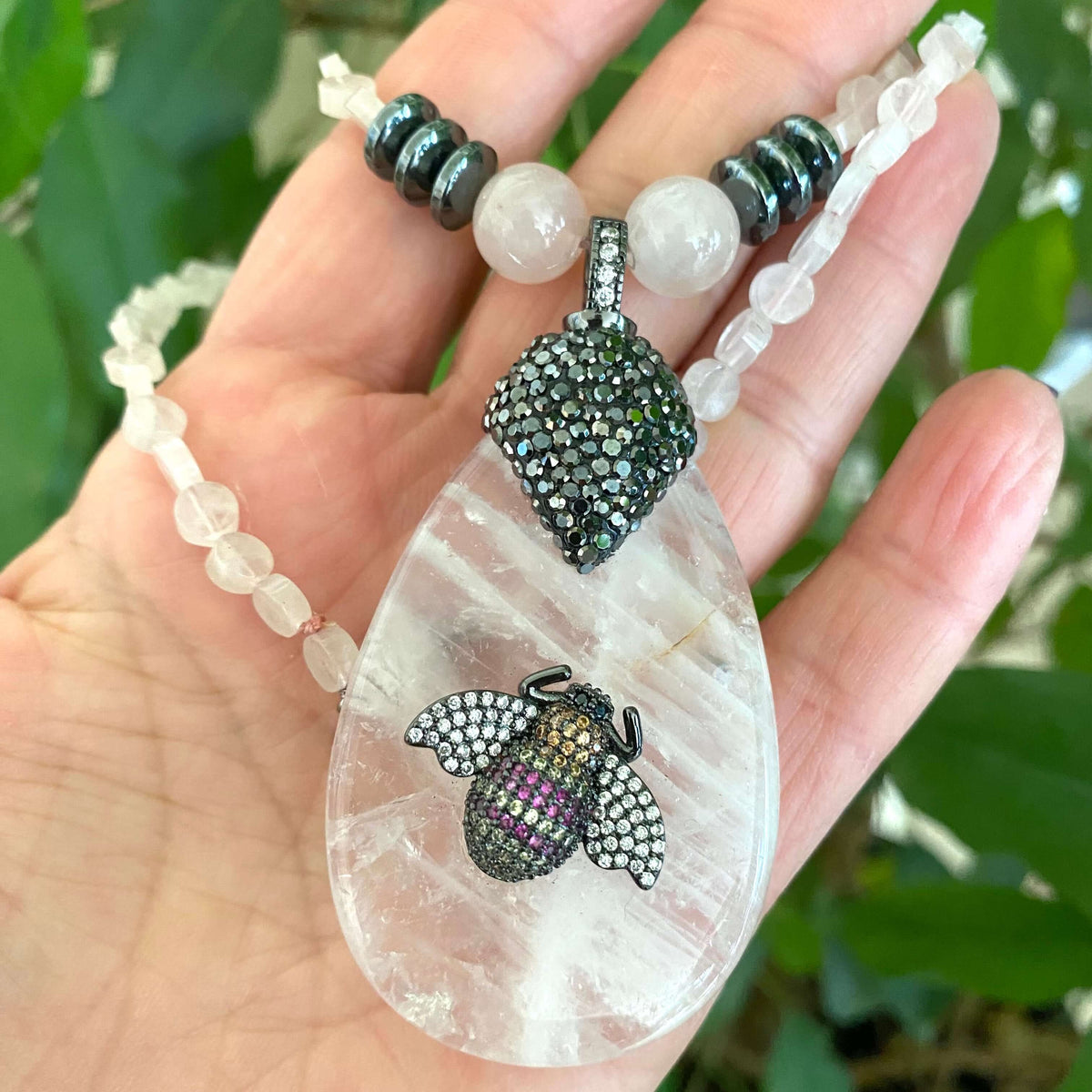 Rose quartz necklace with rhinestone pavé bee pendant showcasing elegant design and soft blush tones.
