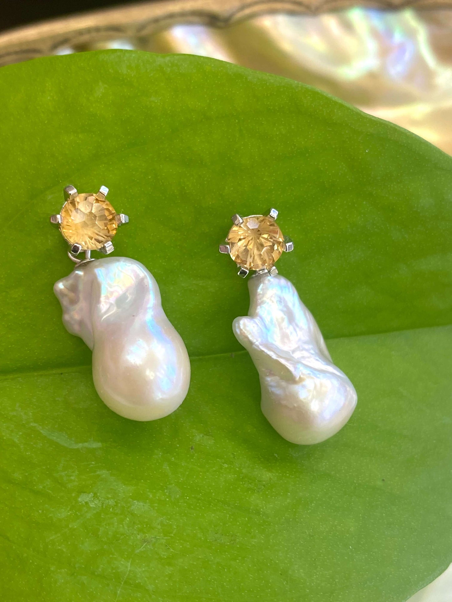 Citrine stud earrings with removable baroque pearl drops on green leaf backdrop
