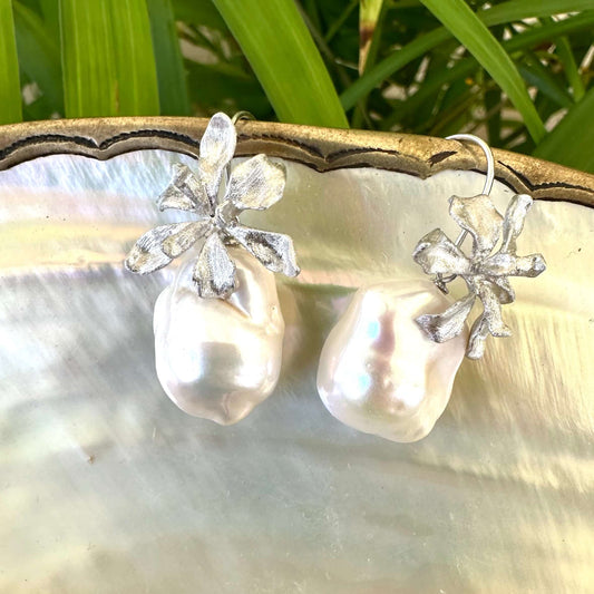 Silver baroque pearl drop earrings on white pearl and green leaf background