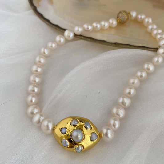 White potato pearl necklace with gold focal accent showcased on a soft backdrop, emphasizing its elegant design and natural beauty.