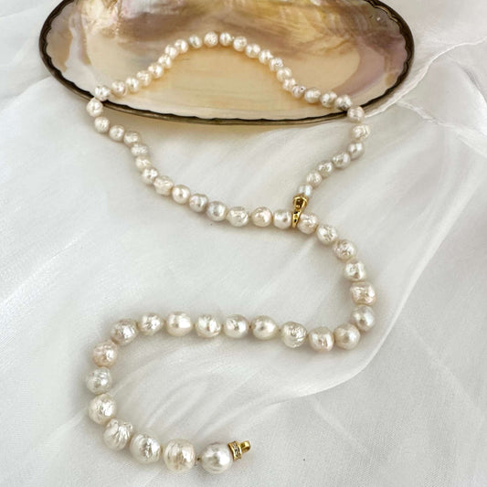 Edison pearl Y necklace featuring organic baroque pearls displayed on an elegant shell plate.