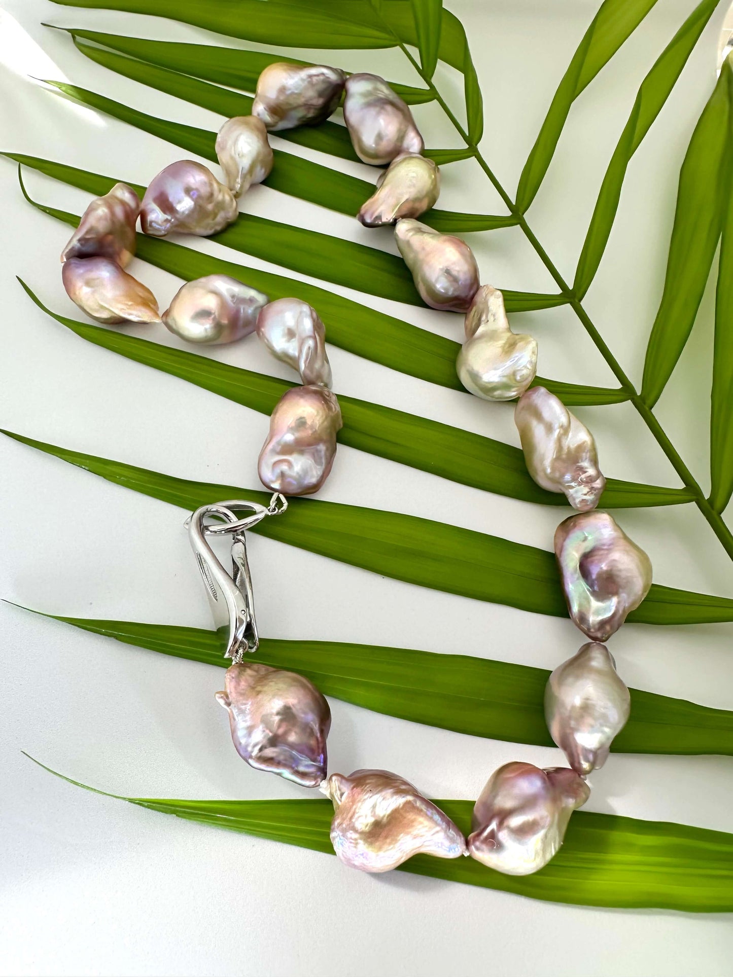 Baroque pearl necklace on a leaf with a white background
