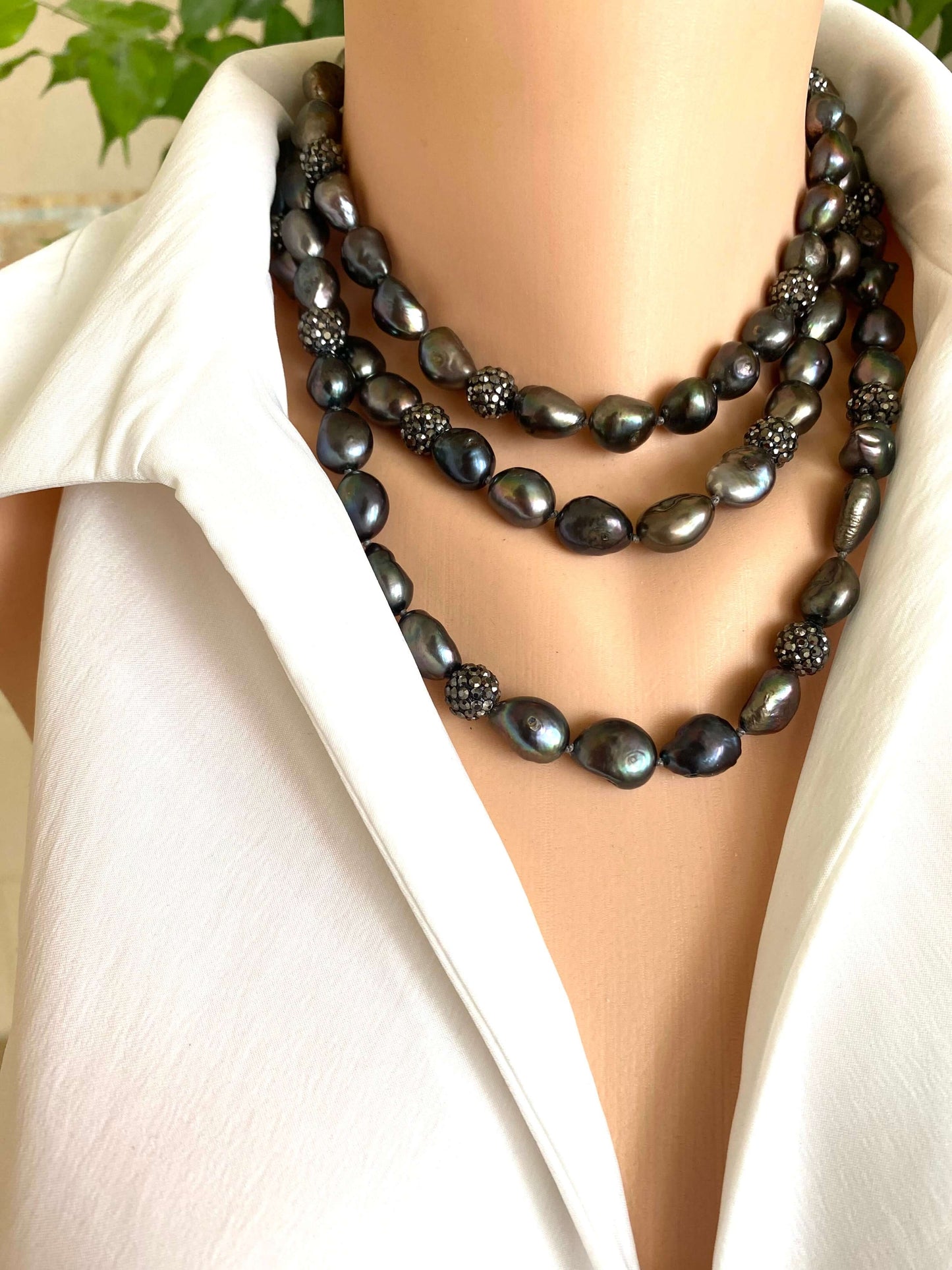 Very long peacock pearl necklace with rhinestone spacer beads showcased on a mannequin against a light background.