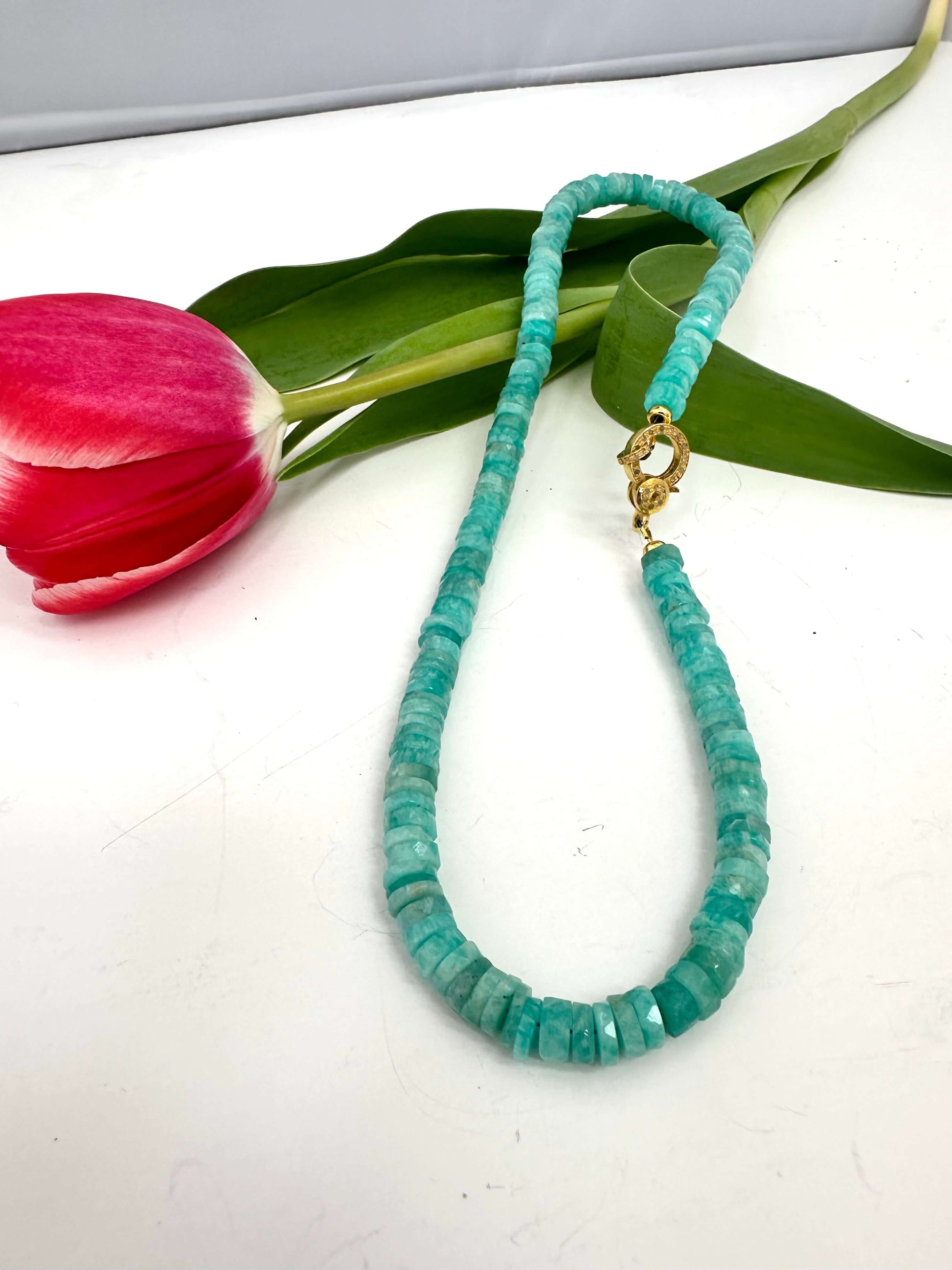 Blue amazonite gemstone necklace with diamond pavé gold vermeil clasp and pink tulip background.
