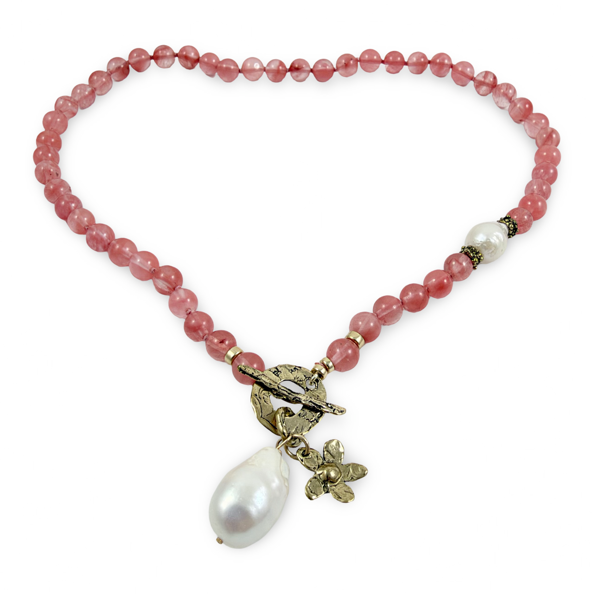 A beaded necklace made of round dusty pink beads, featuring a toggle clasp with a small bird and floral charm, and a large white baroque pearl drop pendant, shown on a plain white background.
