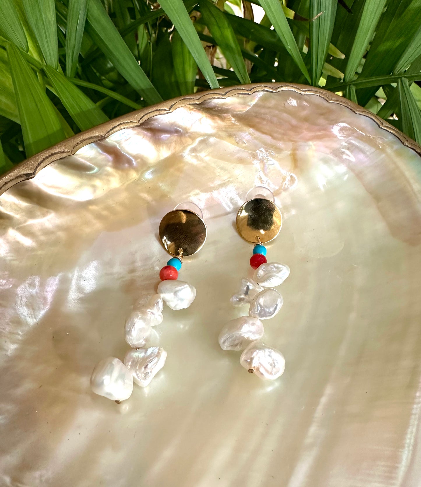 Baroque Keshi Pearl Earrings photographed on pearl shell with green foliage, freshwater pearls and gold brass details