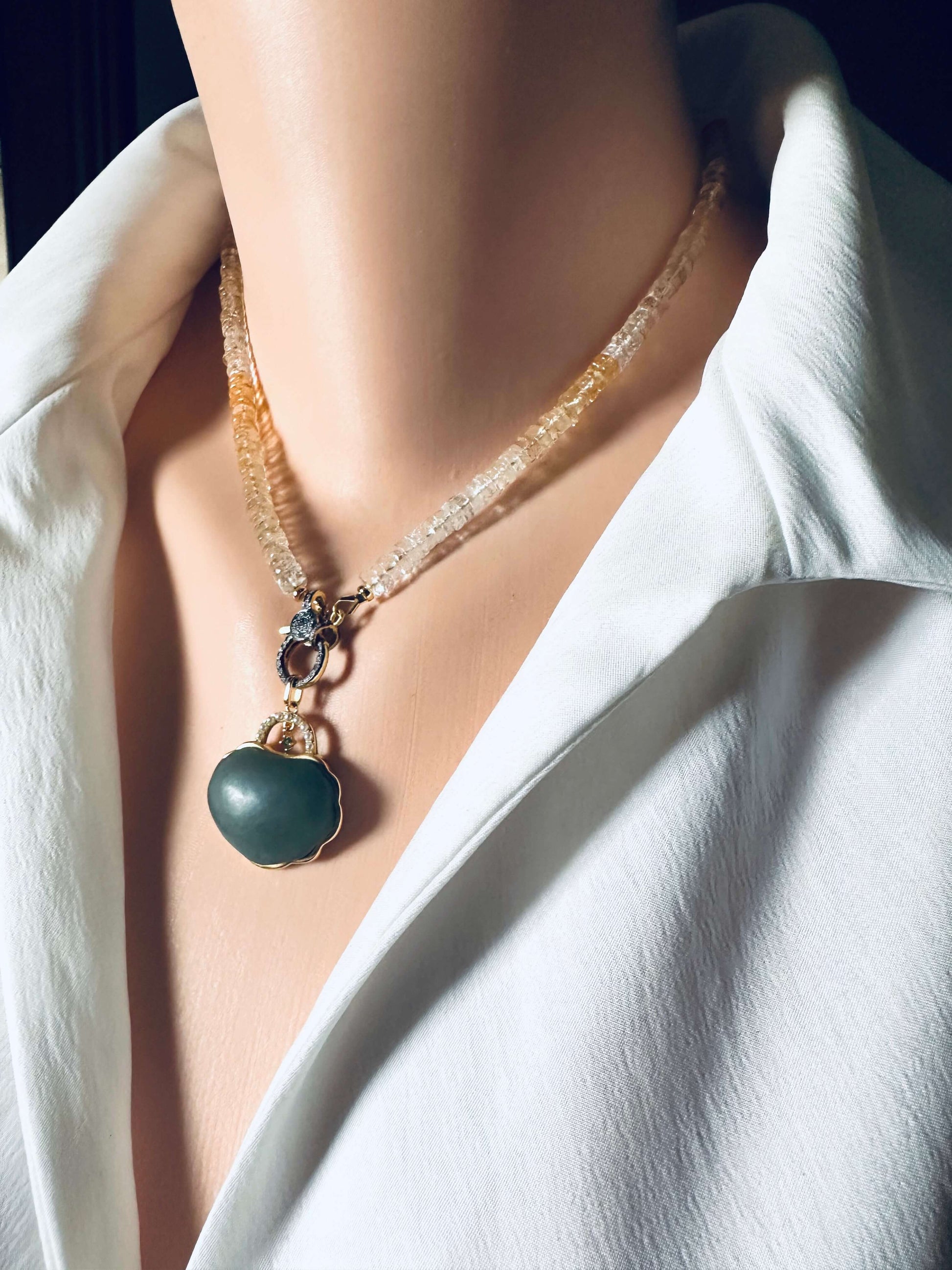 Hotan jade purse pendant with pearl detail hanging from a necklace on a mannequin's neck.