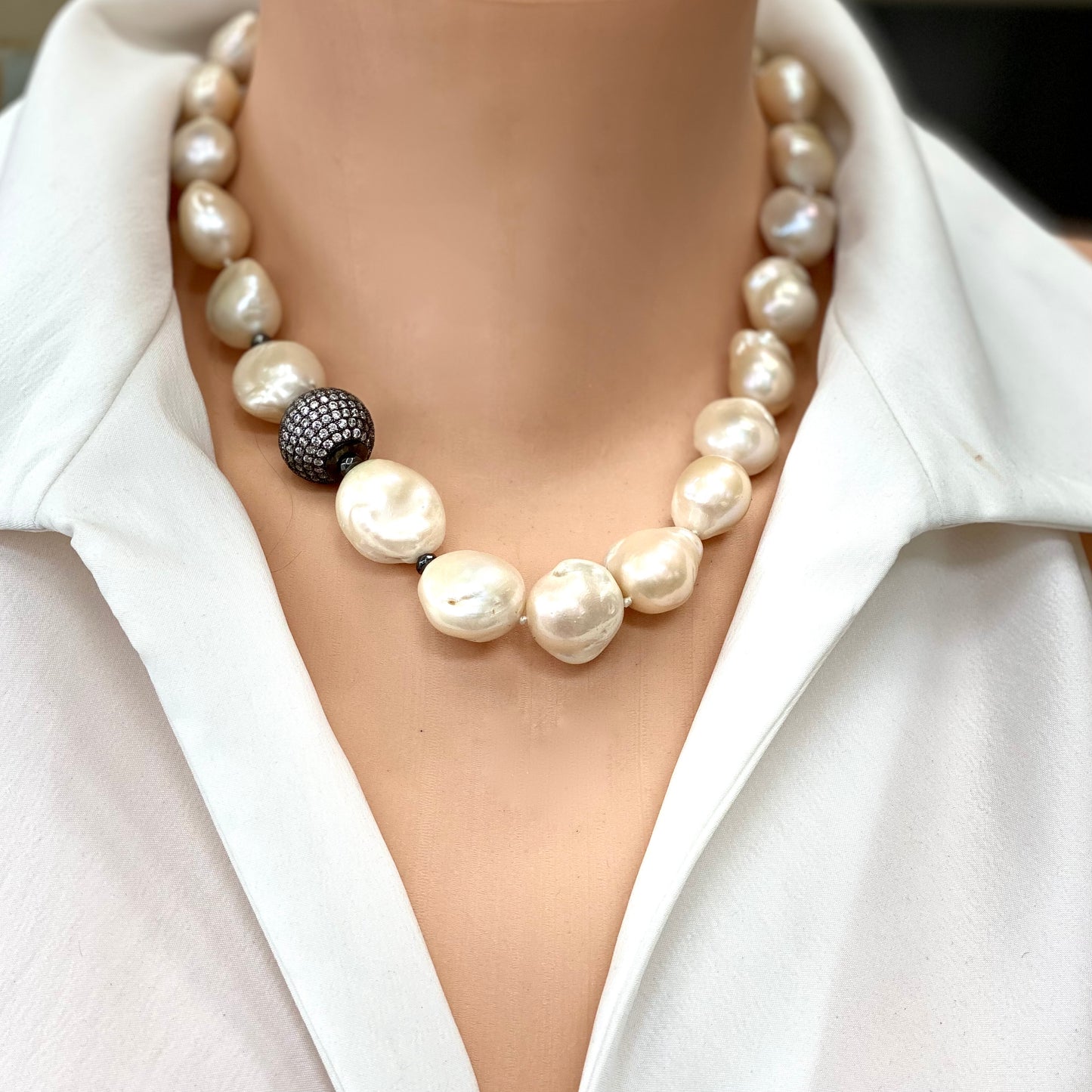 Ivory baroque pearl bridal necklace styled at the collarbone with luminous hand-knotted pearls