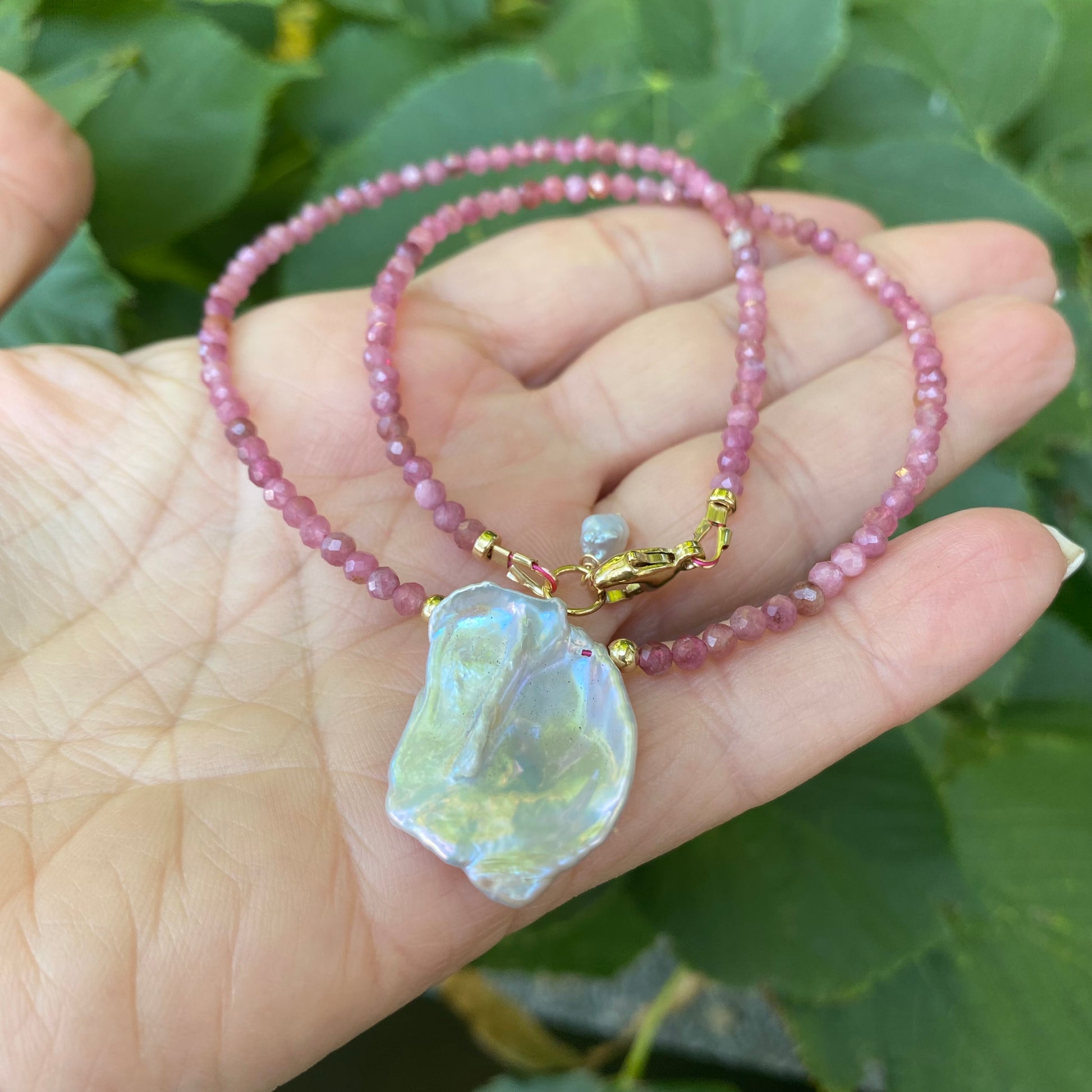 Pink tourmaline keshi pearl choker necklace held in hand showing lavender keshi pearl pendant