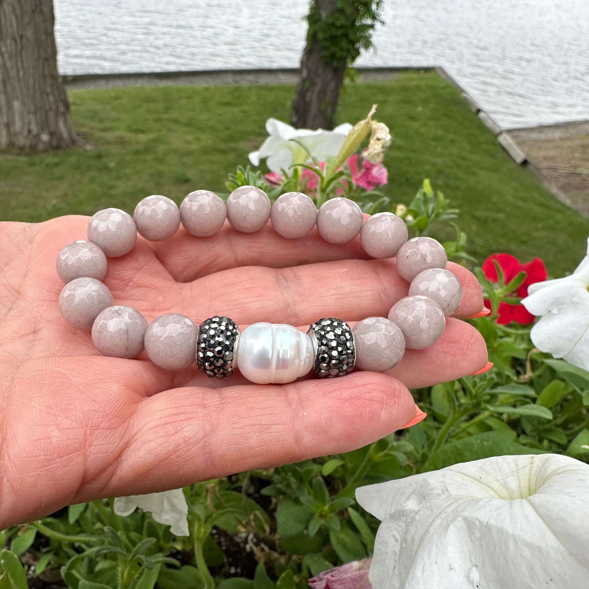 Close up of pink jade pearl bracelet outdoors with greenery