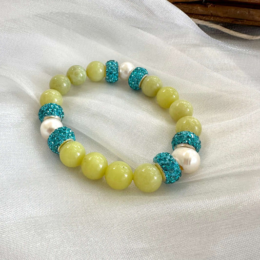 Olive green jade bracelet with three pearls displayed on white cloth