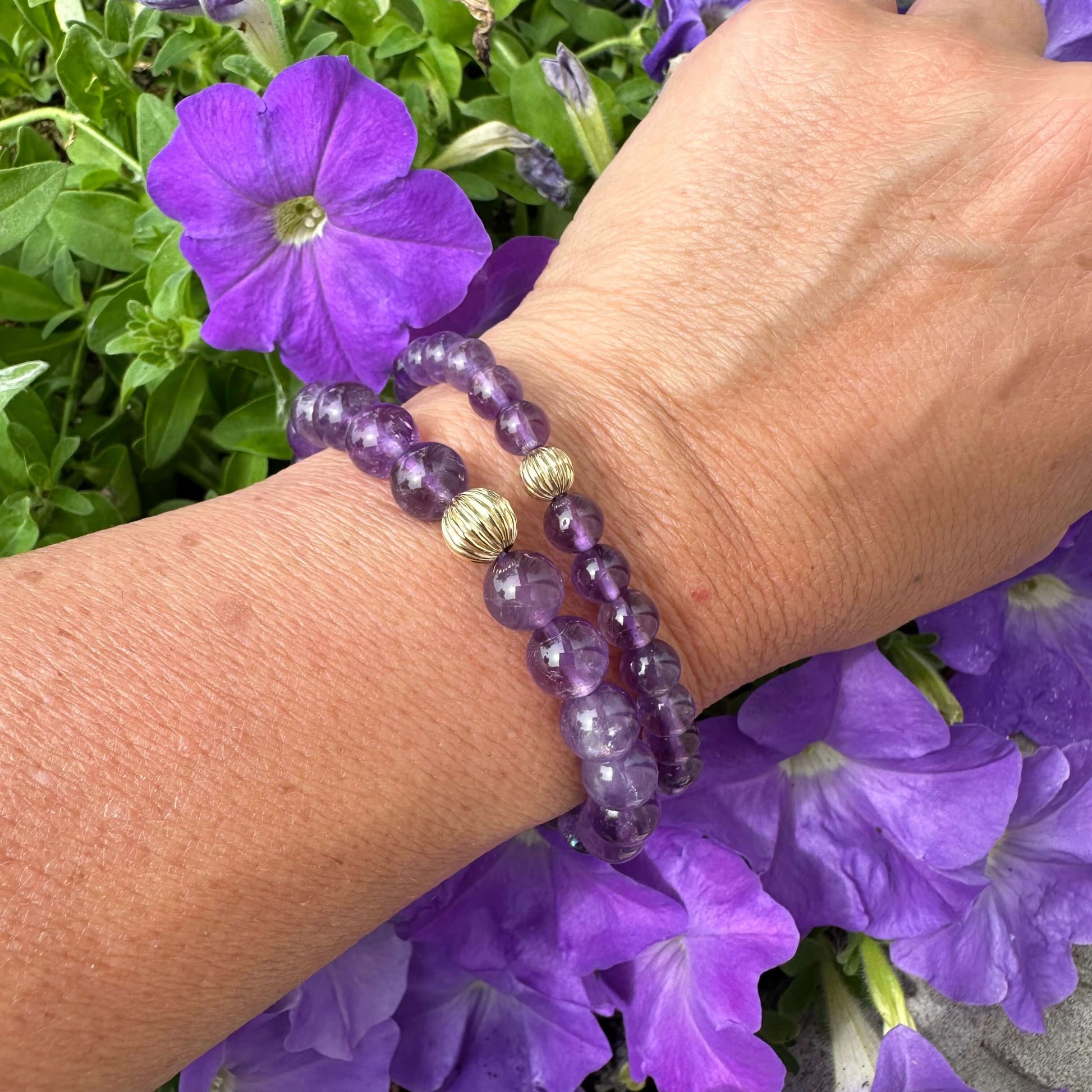 Amethyst bracelet worn on female wrist stacked with a second amethyst bracelet