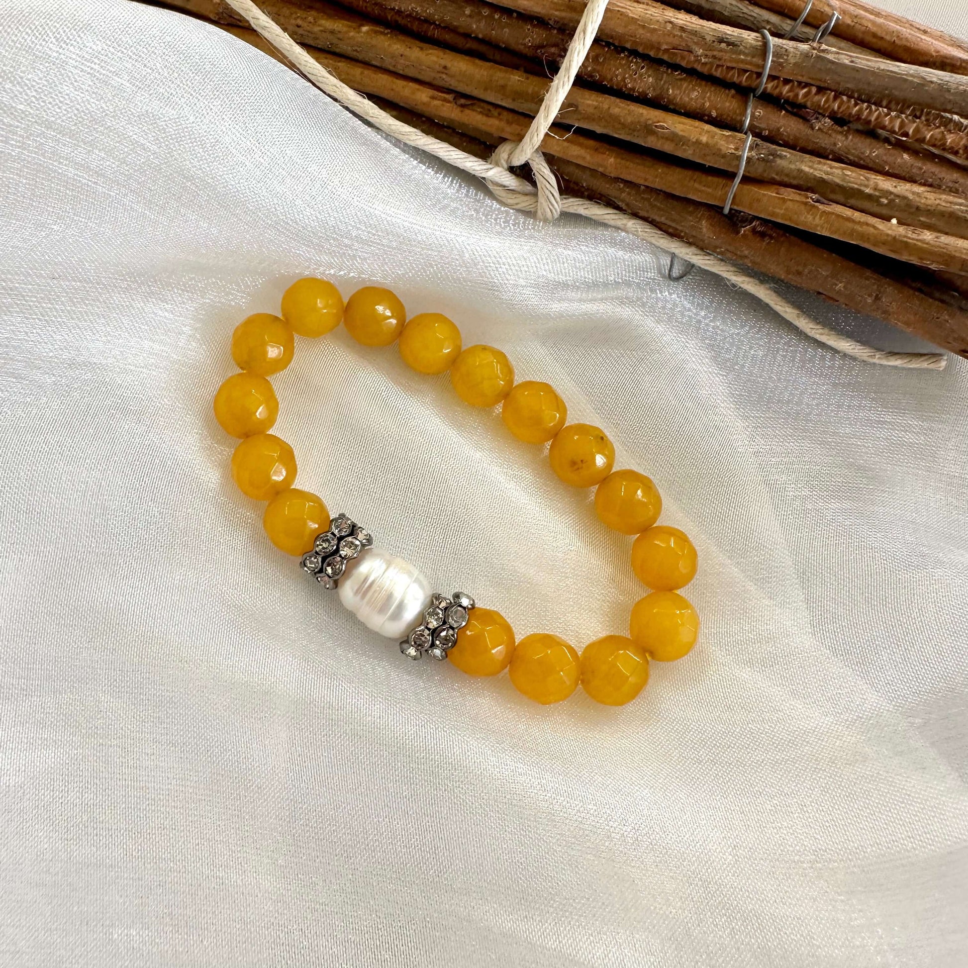 Close-up of yellow jade pearl bracelet on white fabric
