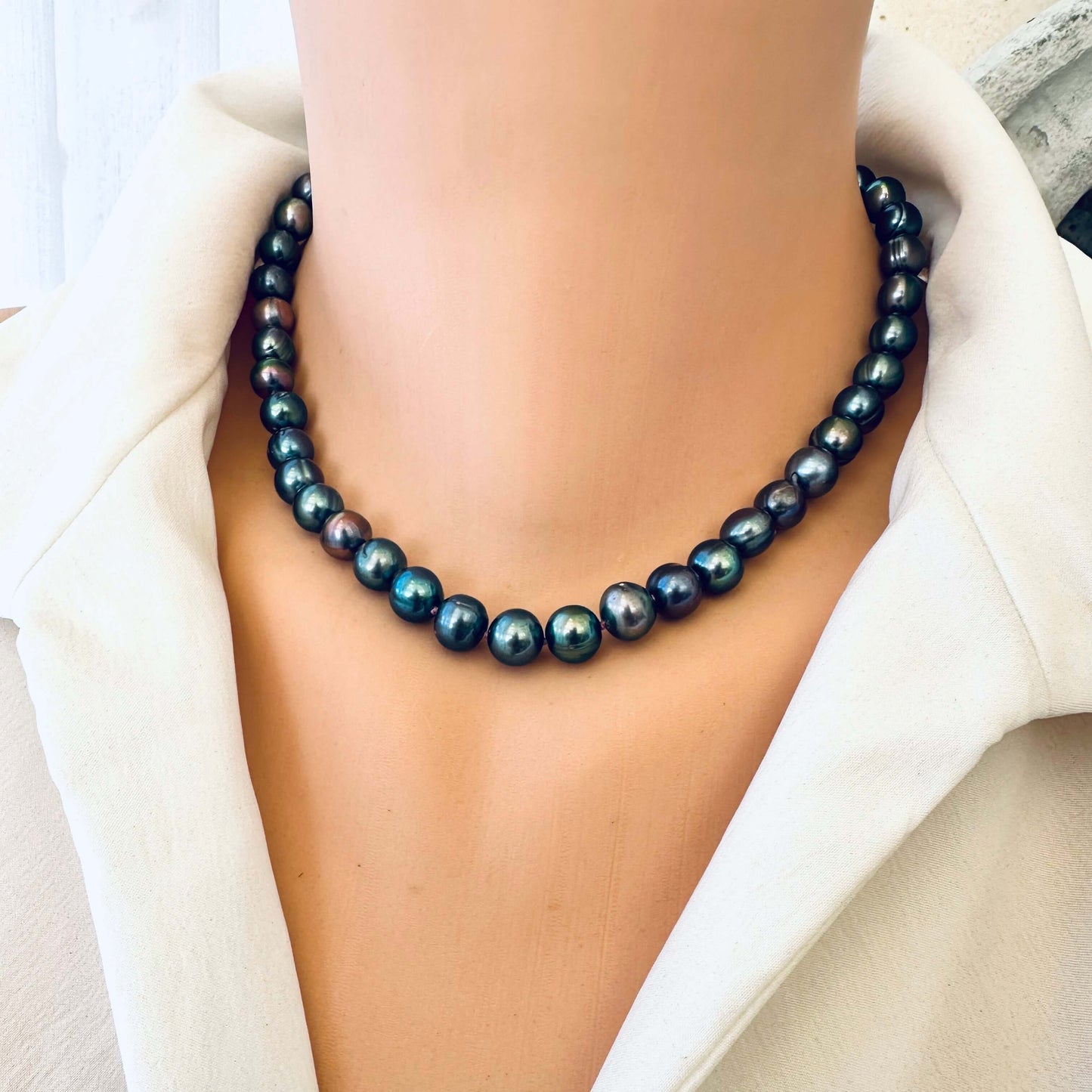 Frontal close up of peacock pearl necklace on mannequin