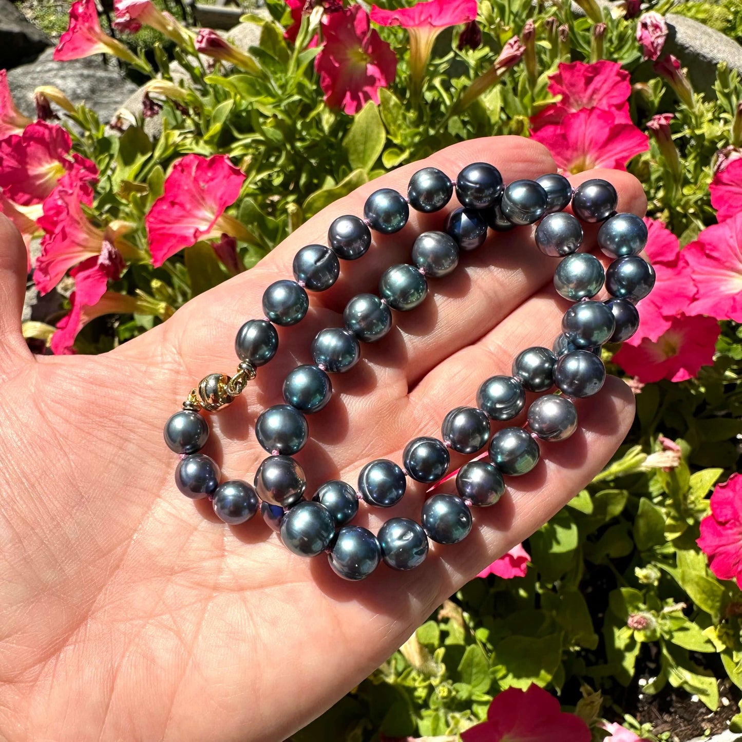 Close up of peacock pearl necklace outdoors with greenery