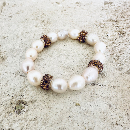 White pearl stretch bracelet with gold rhinestones on white tabletop