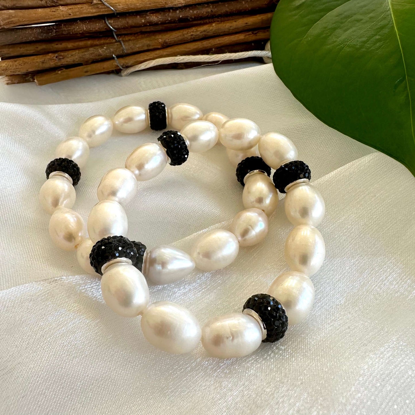 White pearl stretch bracelet with black rhinestones displayed on white cloth