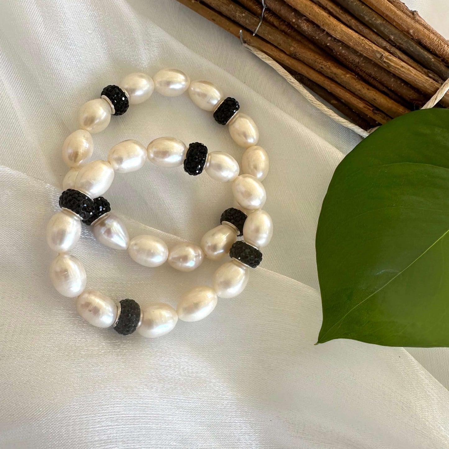 White pearl stretch bracelet with black rhinestones photographed on white cloth backdrop