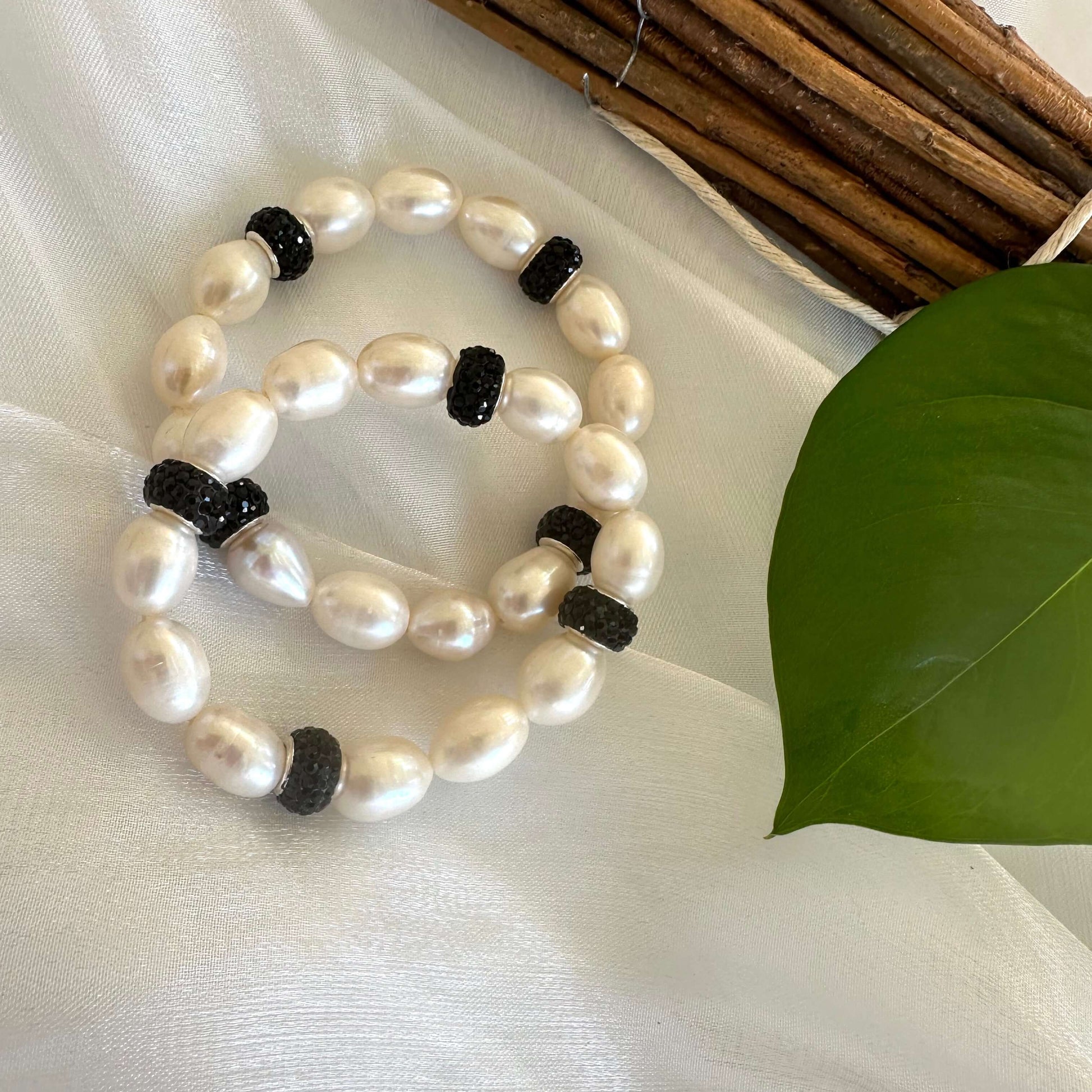 White pearl stretch bracelet with black rhinestones photographed on white cloth backdrop