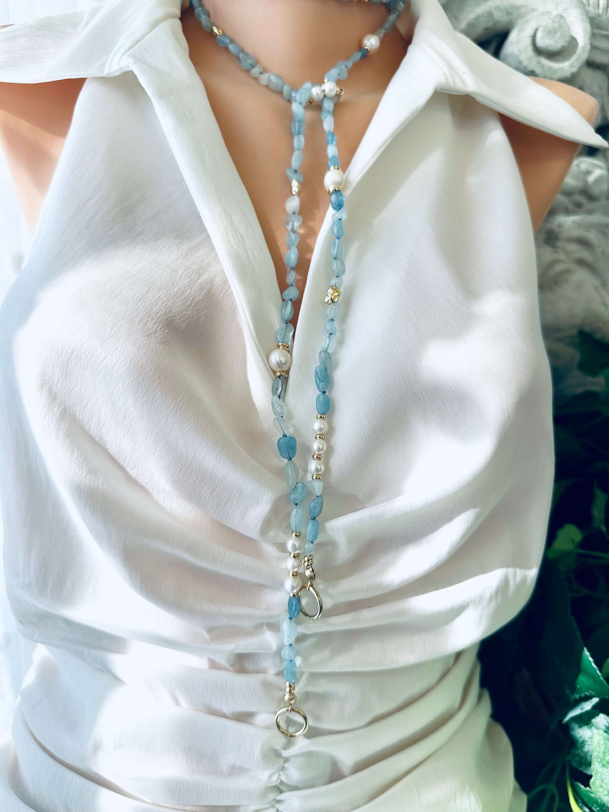 Full-length aquamarine and pearl necklace displayed on mannequin