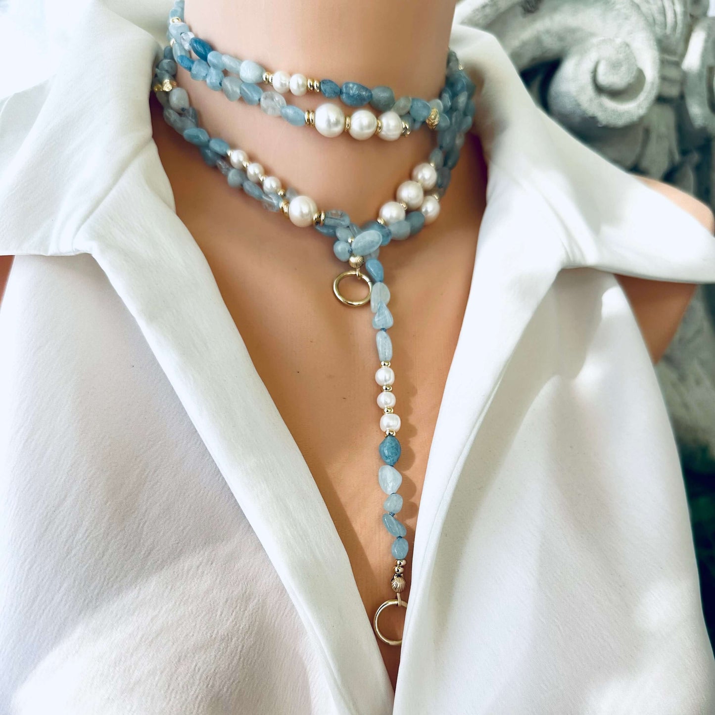 Aquamarine and pearl necklace wrapped tightly around neck with long strand hanging