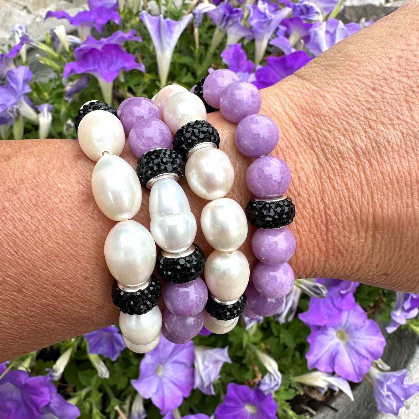 White pearl stretch bracelet with black rhinestones worn on woman's wrist stacked with similar bracelet