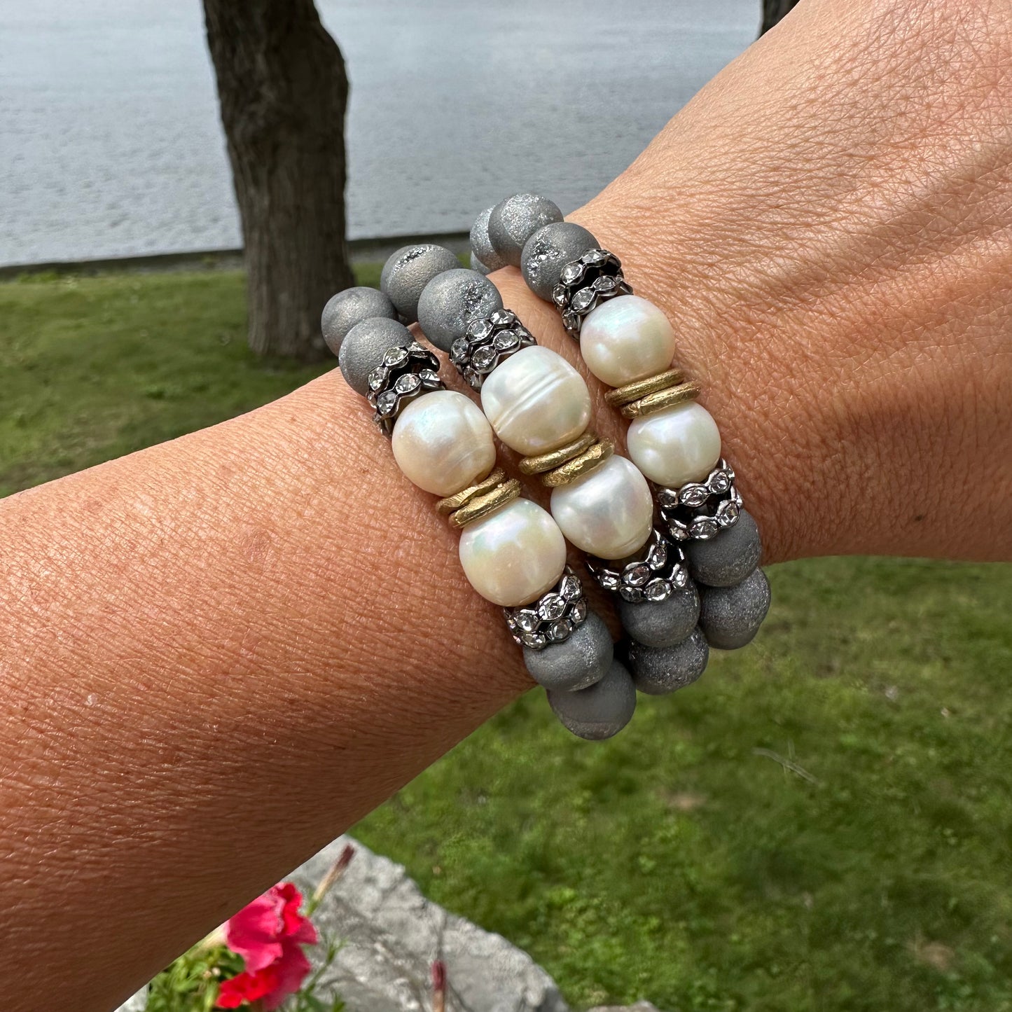 Three grey druzy agate and pearl bracelets worn on female model’s wrist