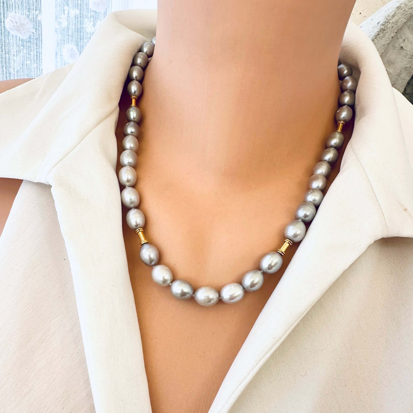 Front close-up of grey pearl necklace with gold details on mannequin