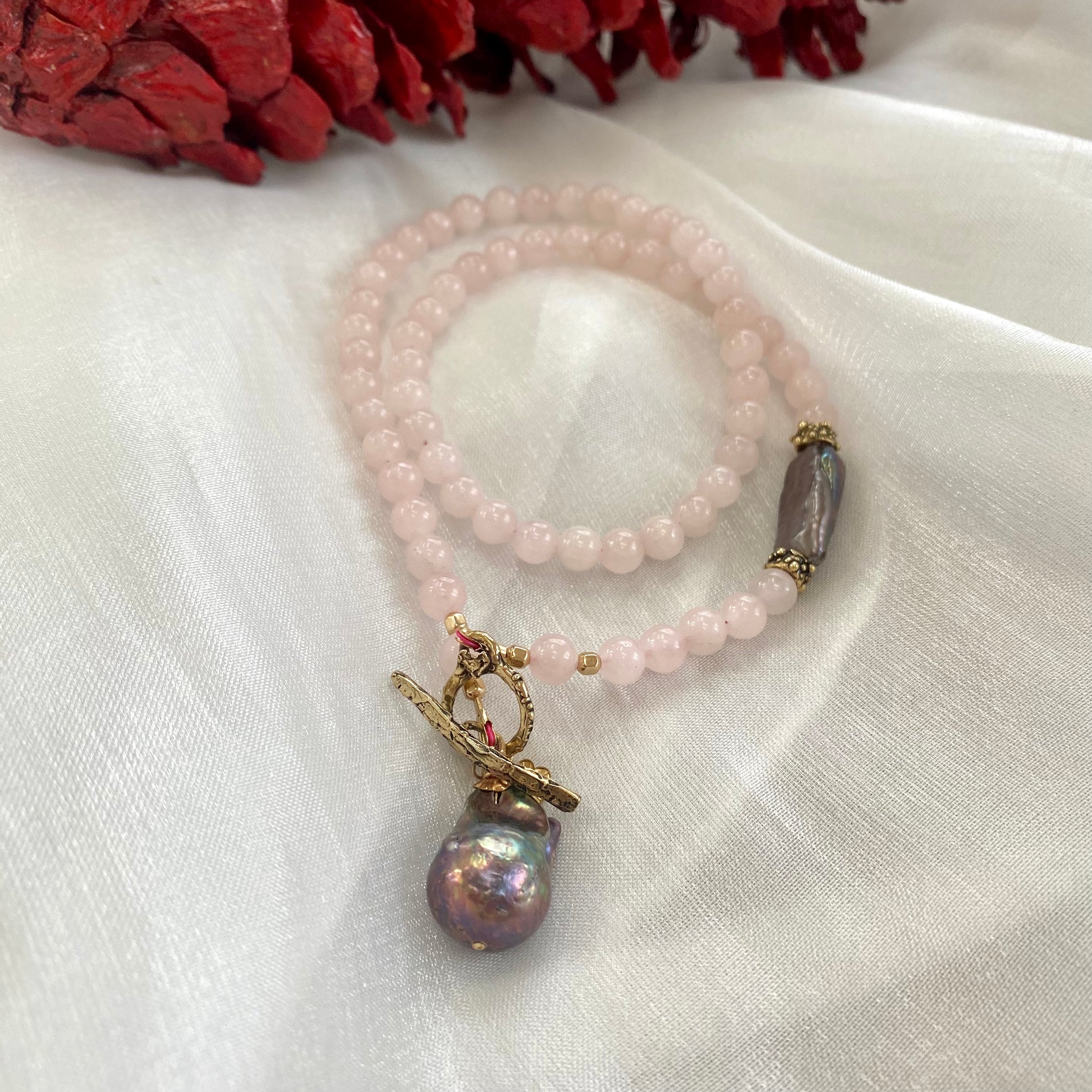 Rose quartz toggle necklace with black baroque pearl, showcasing delicate design and blush-pink tones.