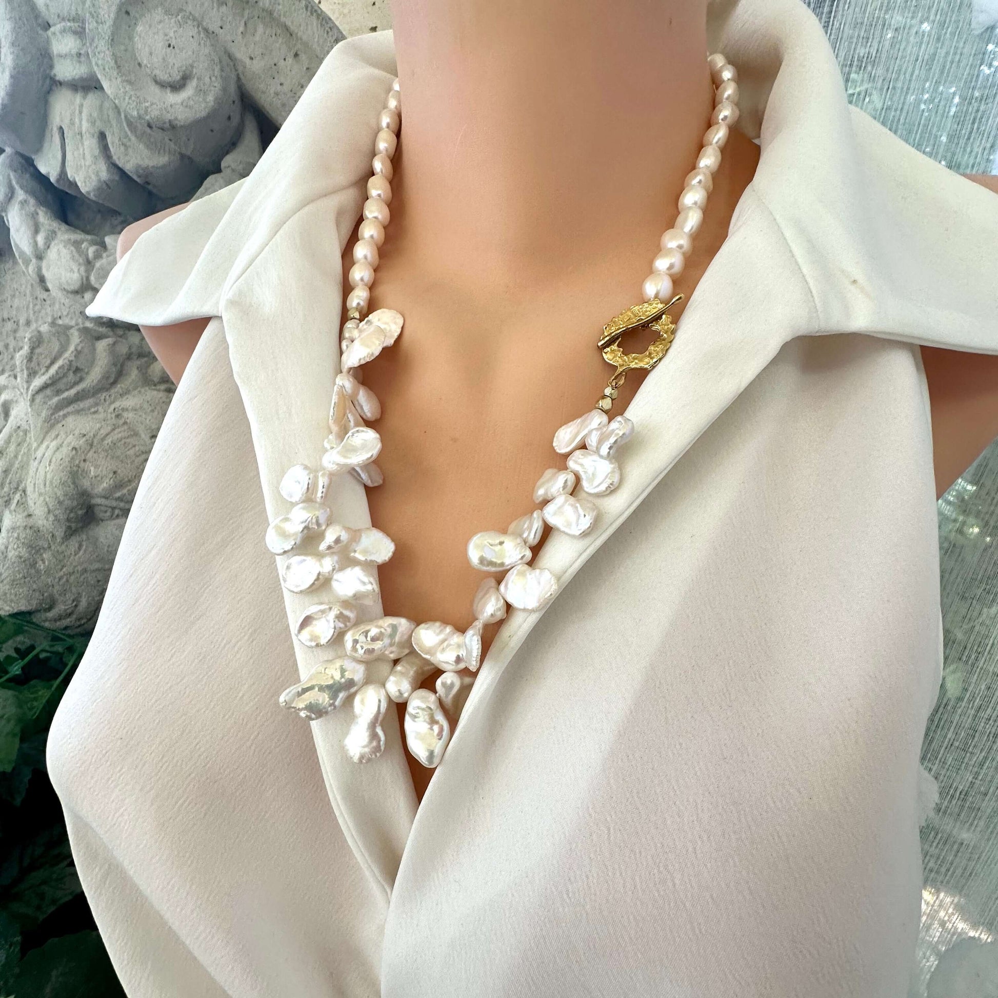 White keshi pearl necklace worn by mannequin, side close-up showing petal pearls and golden clasp