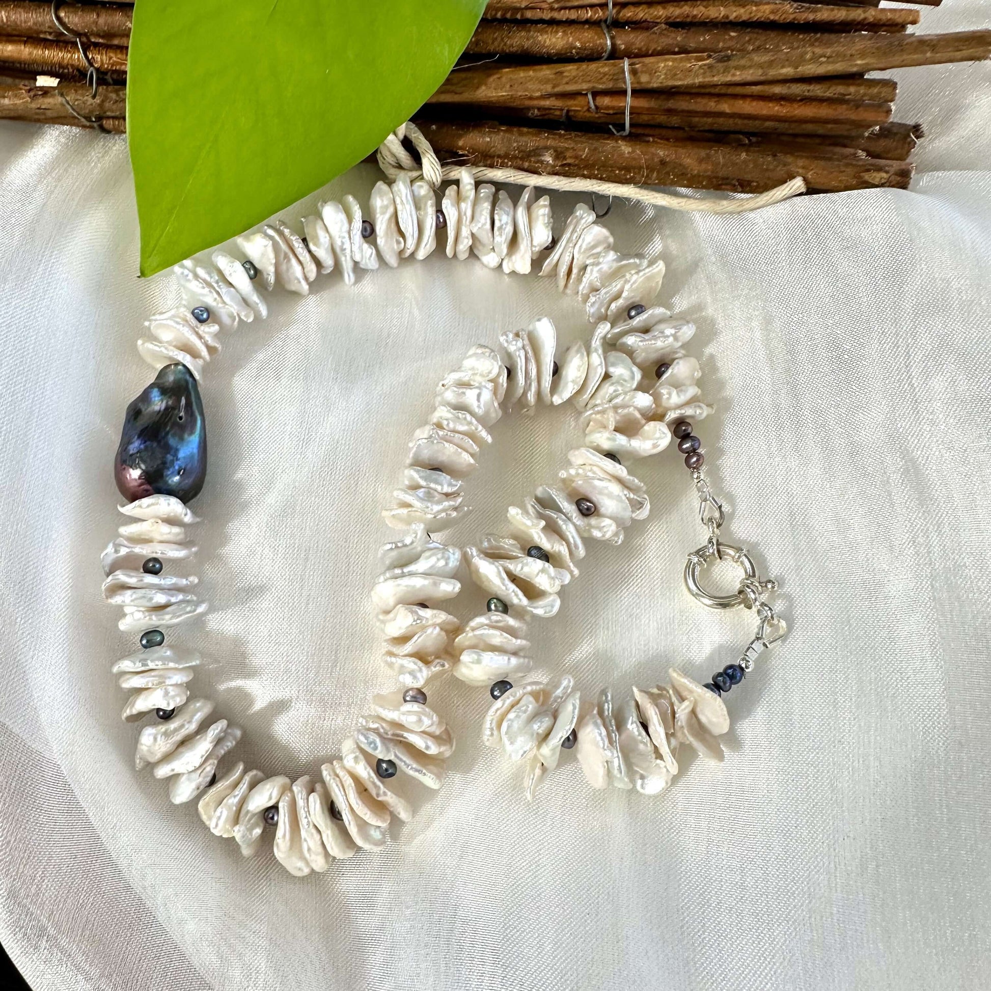 White cornflake pearl necklace with black baroque pearl pendant, showcasing unique textures and organic beauty.