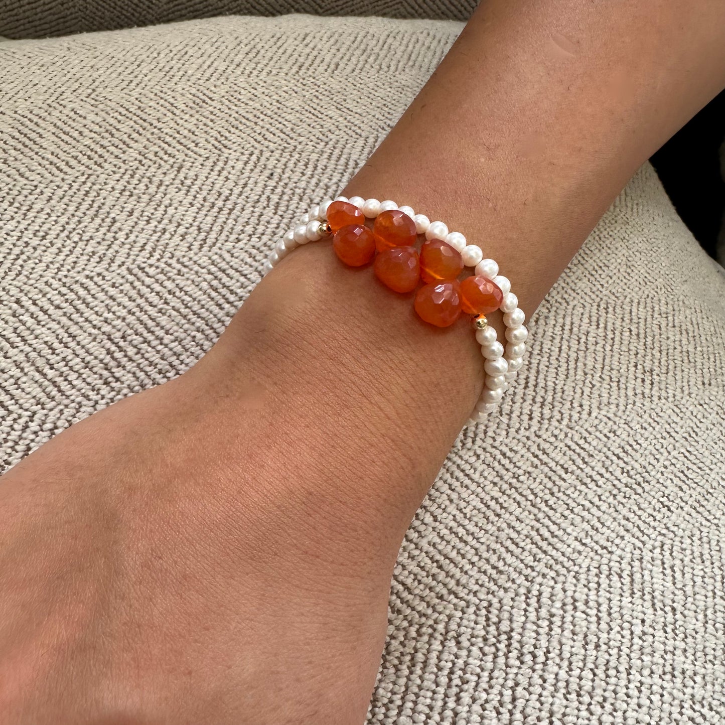 Close-up of double strand pearl bracelet on wrist showing pearls and orange Carnelian stones