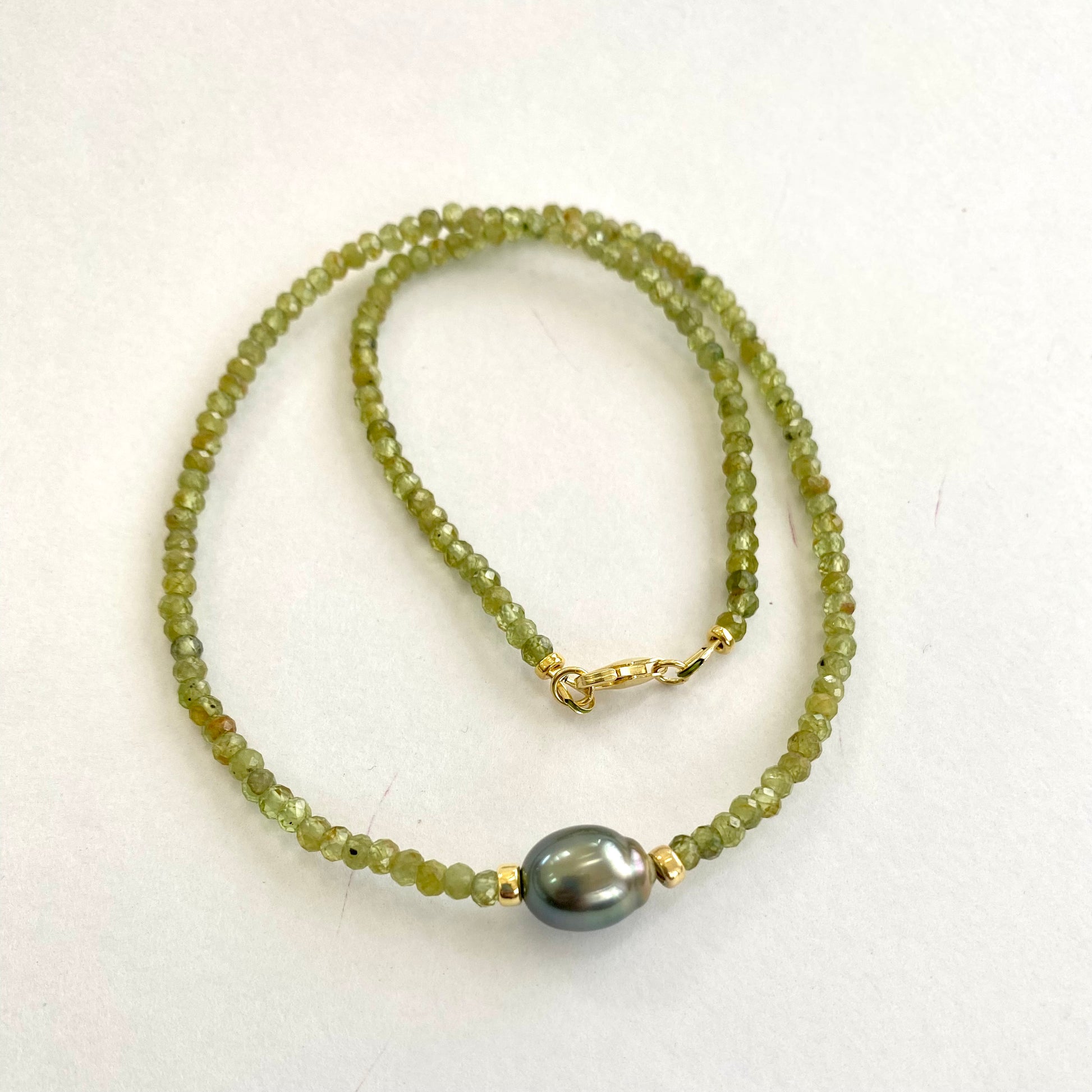 Peridot baroque pearl necklace featuring vibrant green Peridot beads and a Tahitian pearl centerpiece.