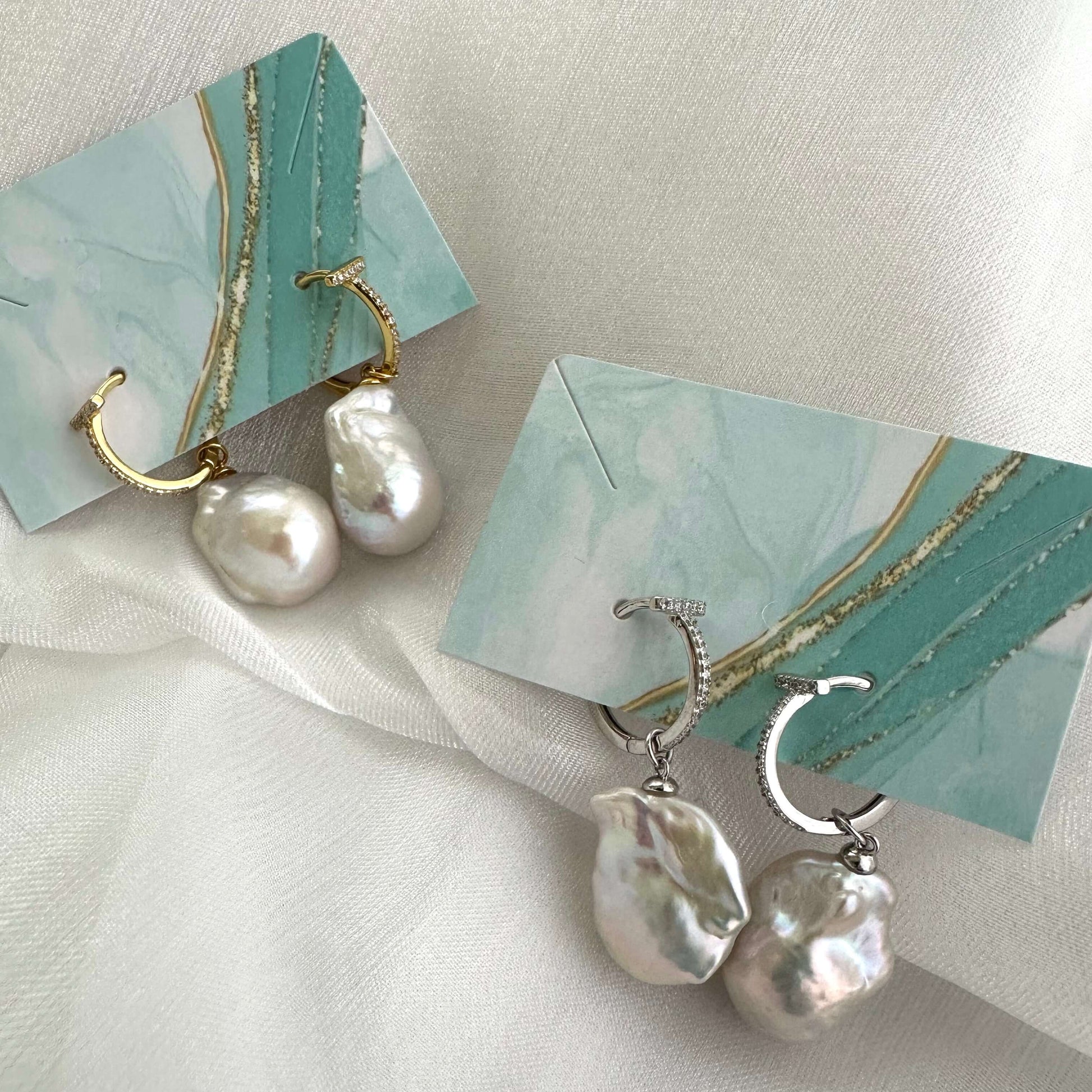 White Baroque Pearl Earrings – silver and gold pairs on turquoise package and white cloth background