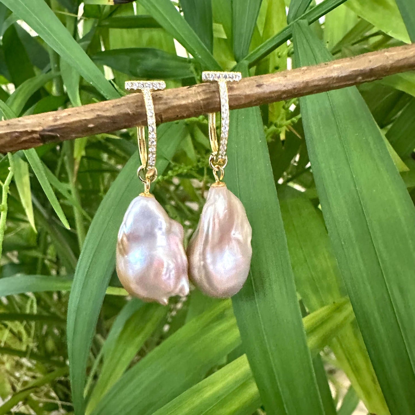 Pink baroque pearl hoop earrings hanging from branch with green leaves, elegant gold vermeil handcrafted jewelry from Canada.