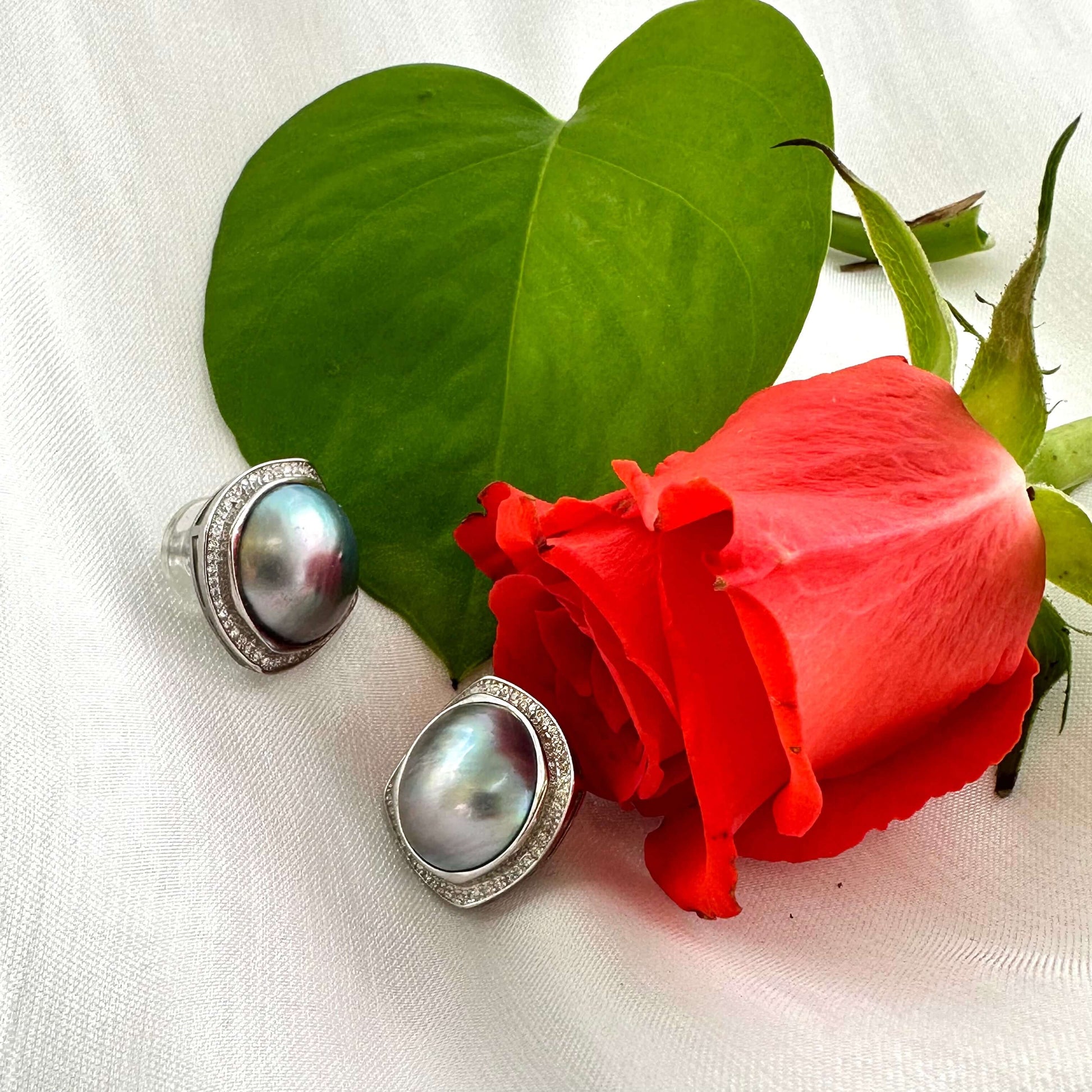 Mabe Pearl Earrings – displayed with red rose and white cloth backdrop