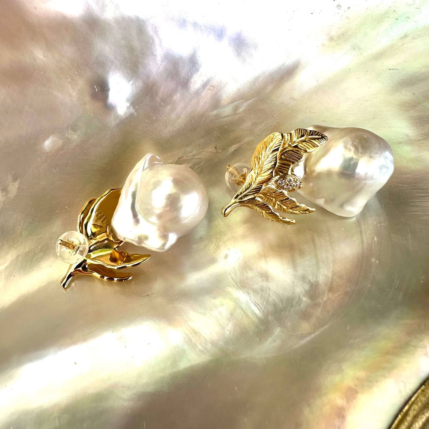 Elegant Baroque Pearl Earrings in 18K gold vermeil oak leaf setting resting on luminous white pearl shell.