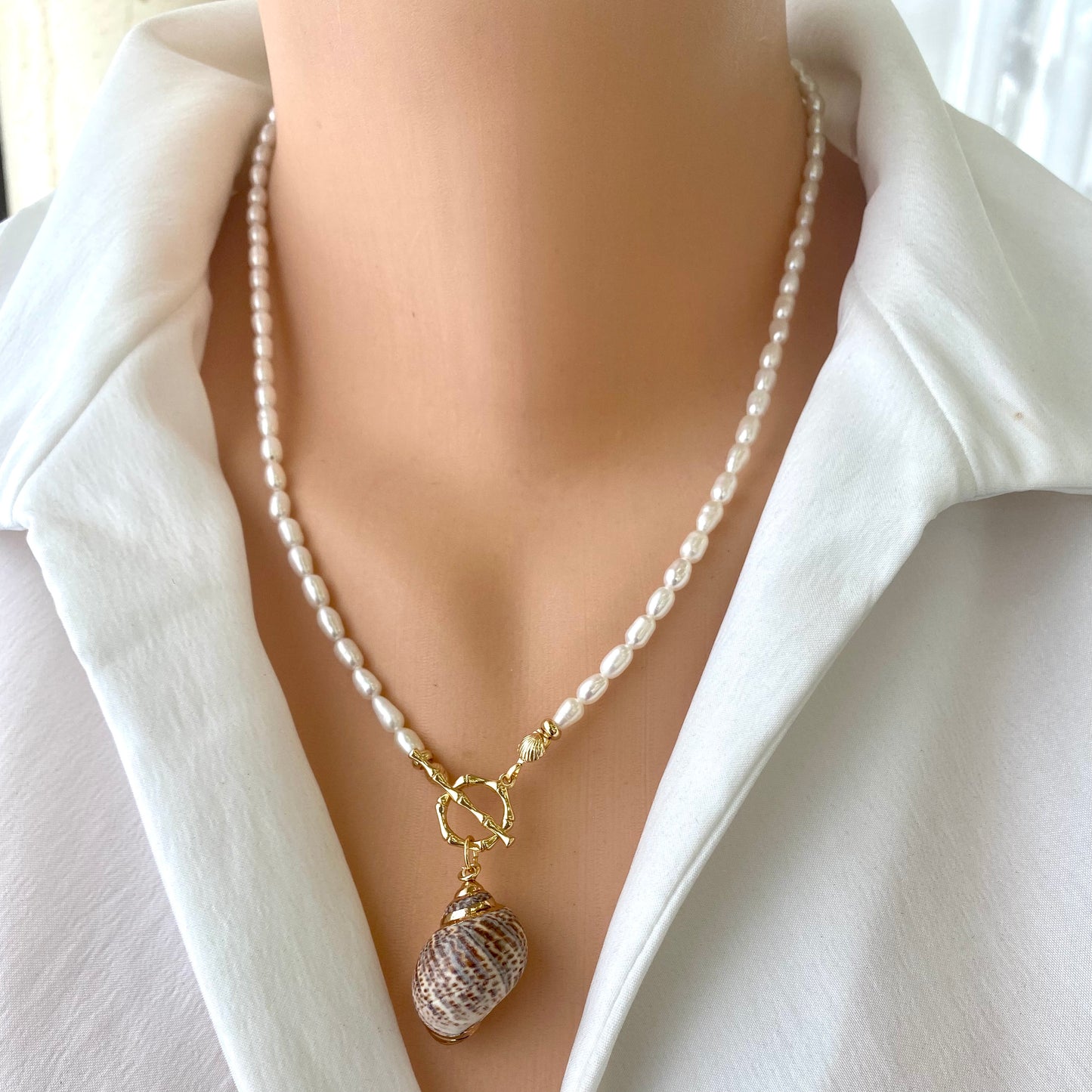 Real seashell pendant pearl necklace styled at the collarbone with classic white pearls