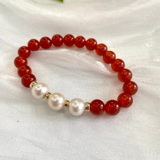 Orange Carnelian Bracelet with three pearls displayed on white cloth – detailed close-up