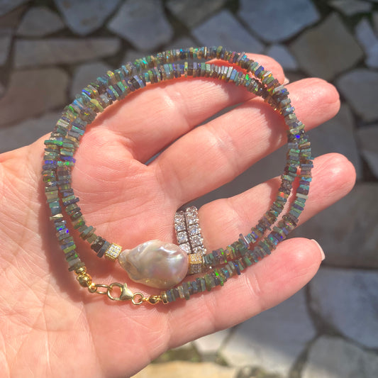 Black opal pearl necklace held in hand against natural background