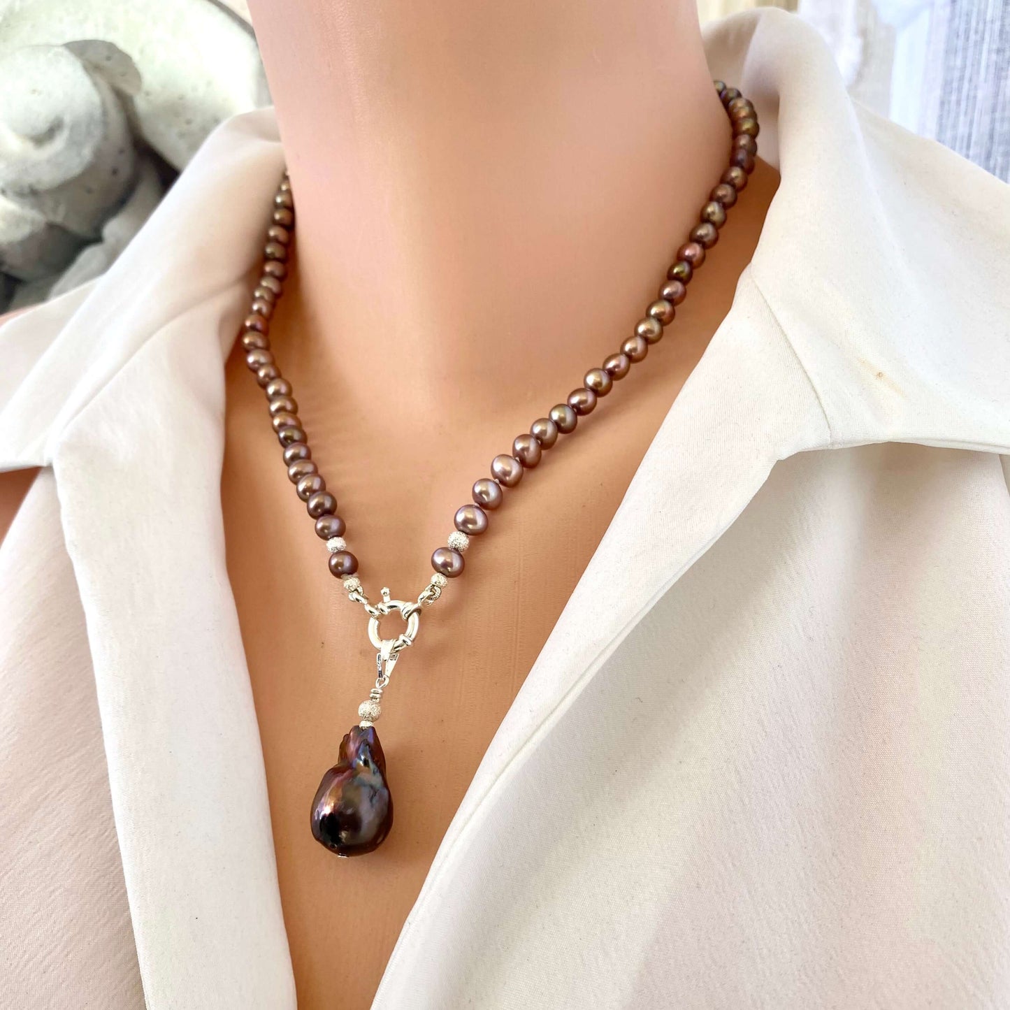 Bronze pearl necklace with brown baroque pendant worn on mannequin, showing deep earthy tones and elegant silver clasp.