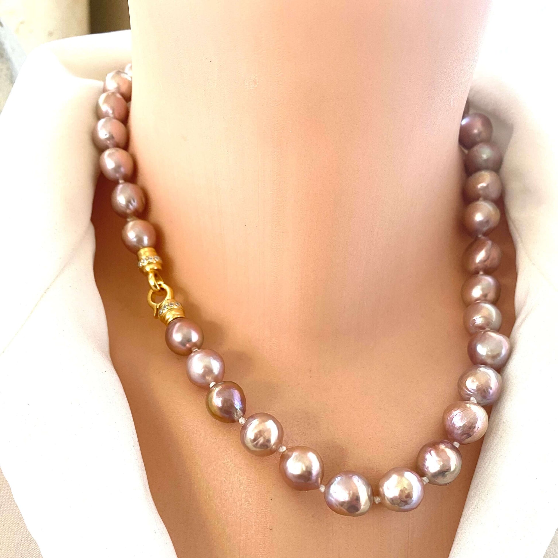 Pink lavender pearl necklace with Edison baroque pearls draped on mannequin, showing luminous surface and silver clasp.