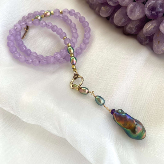 Amethyst Pearl Necklace displayed on white background beside raw amethyst gemstone.