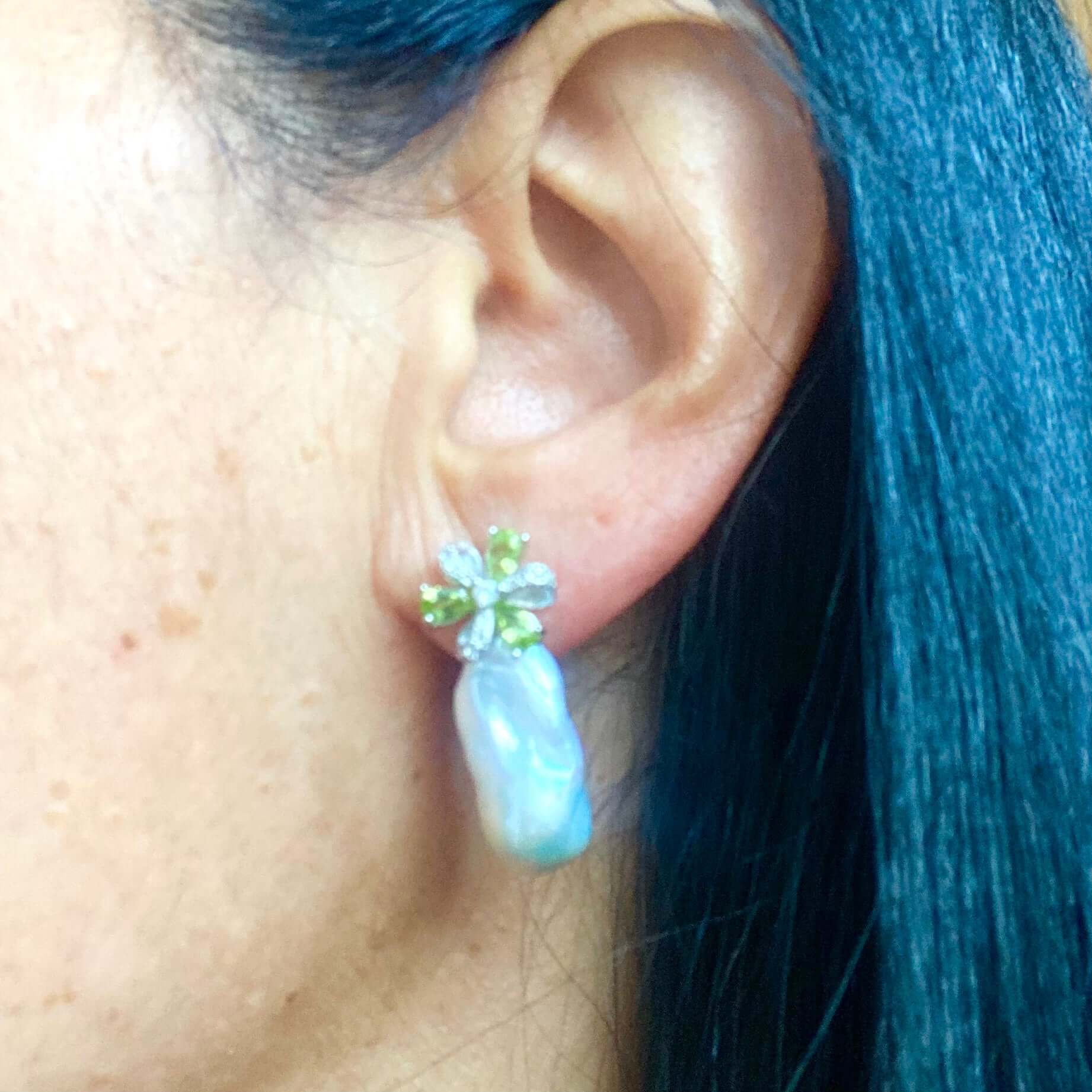Side view of woman wearing Peridot stud earrings with baroque pearl drops