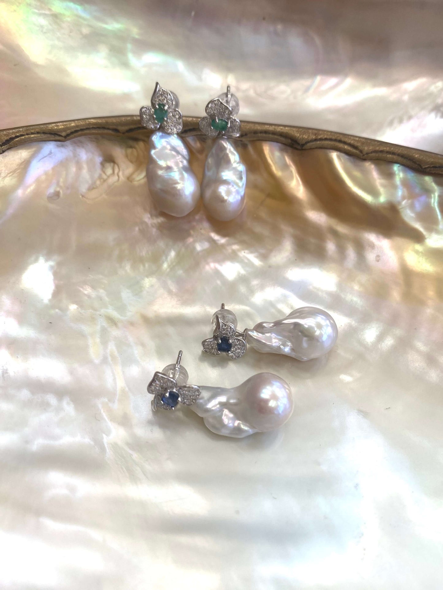 Emerald stud earrings and sapphire stud earrings with pearl drops on pearl shell
