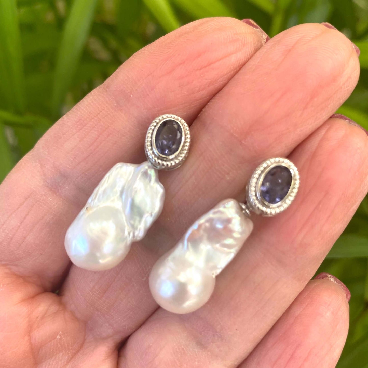Handcrafted iolite baroque pearl drop earrings held in hand — detailed close-up of gemstone studs with removable pearls by Loulia Pearl Jewelry
